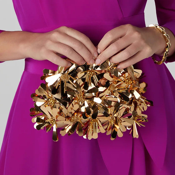 woman in purple dress holding gold giavanna sequin clutch bag